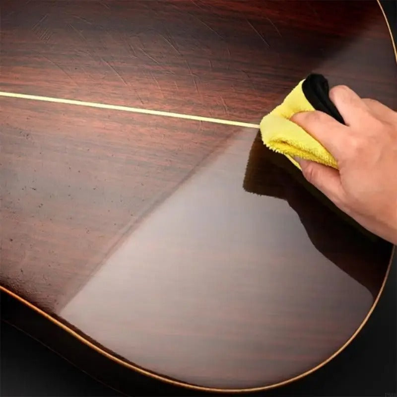 Musicien utilisant huile de soin sur une guitare acoustique en bois.